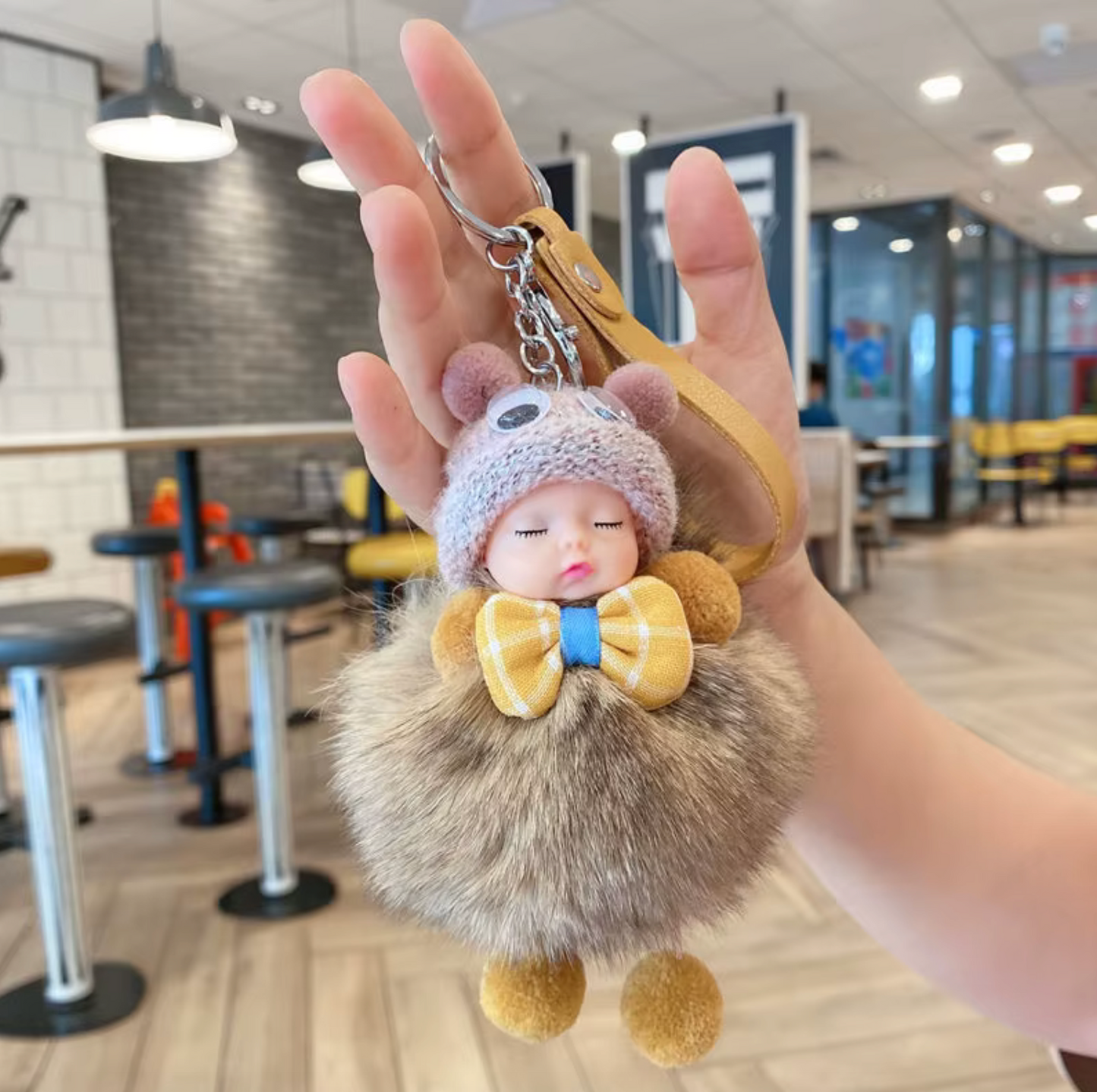 Keychain with plush toy character held in a hand in an indoor setting