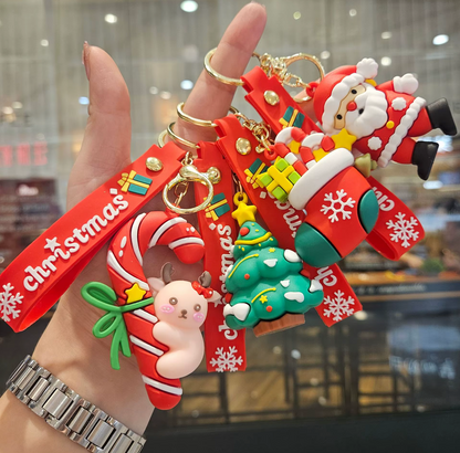 Hand holding a set of Christmas-themed keychains with Santa Claus, candy cane, and tree designs.