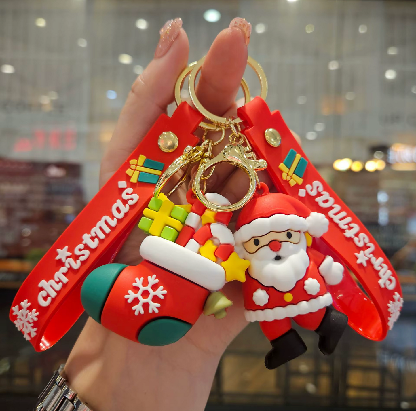 Keychain with Santa Claus and Christmas stocking design held by a hand.