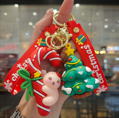 Christmas-themed keychain with Santa Claus, snowman, and tree design held by a hand.