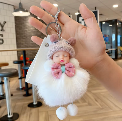 Keychain with a plush doll character held in a hand, indoor setting