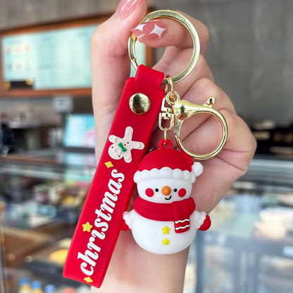 Keychain with snowman charm and 'Christmas' tag held by a hand in a blurred indoor setting