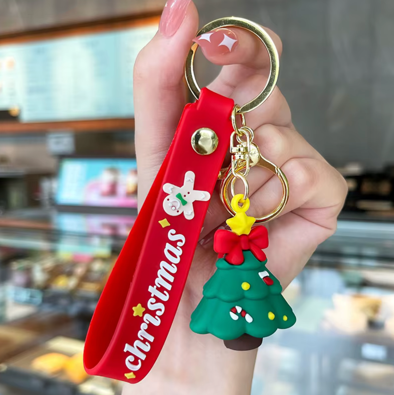 Red 'Christmas' keychain with a green tree charm held in a hand.