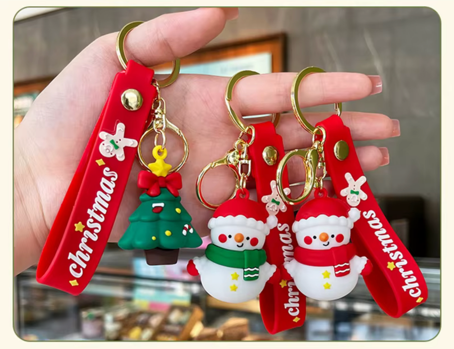 Hand holding Christmas-themed keychains with red straps and festive designs.
