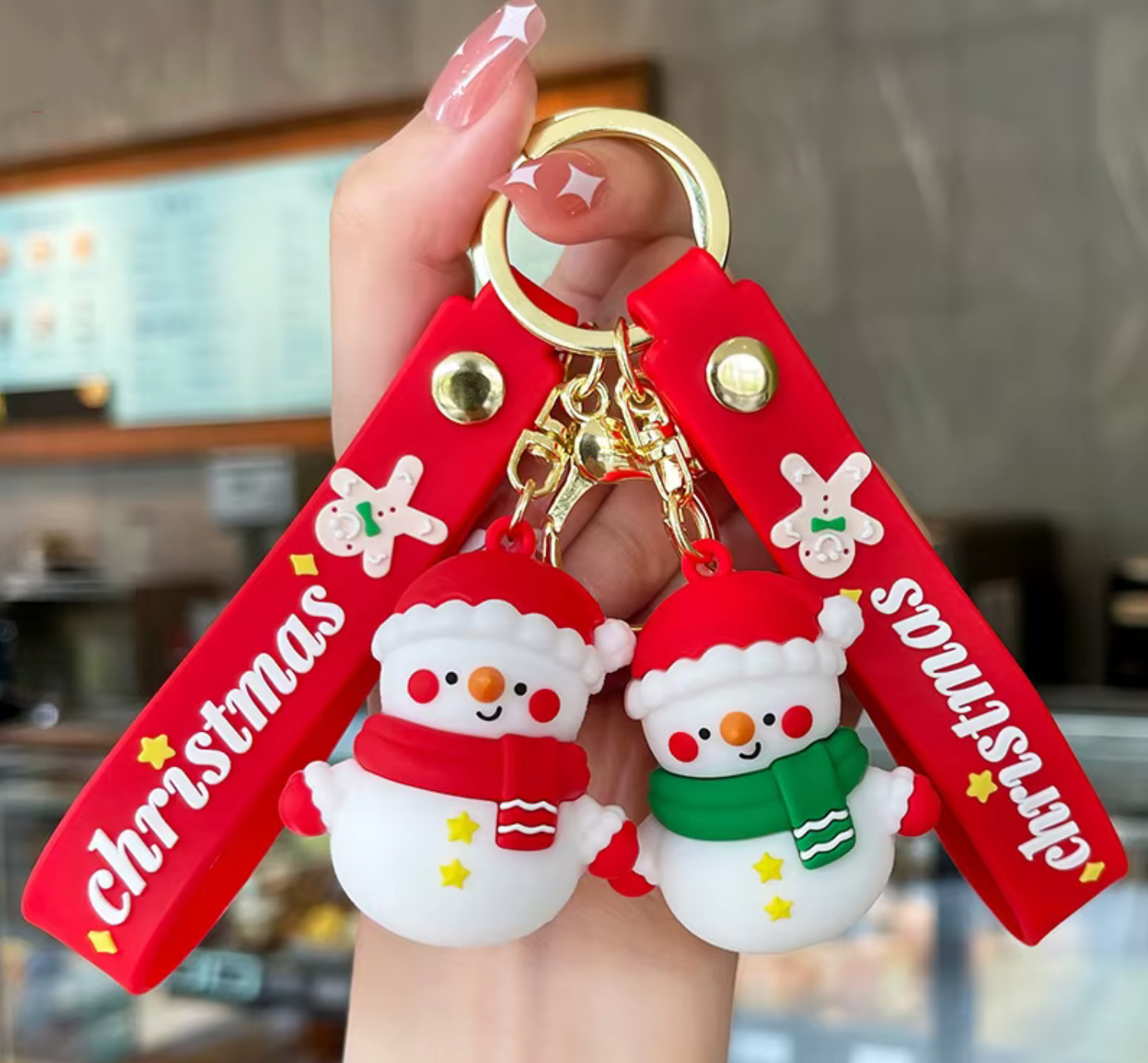 Red 'Christmas' keychain with snowman charms held by a hand.