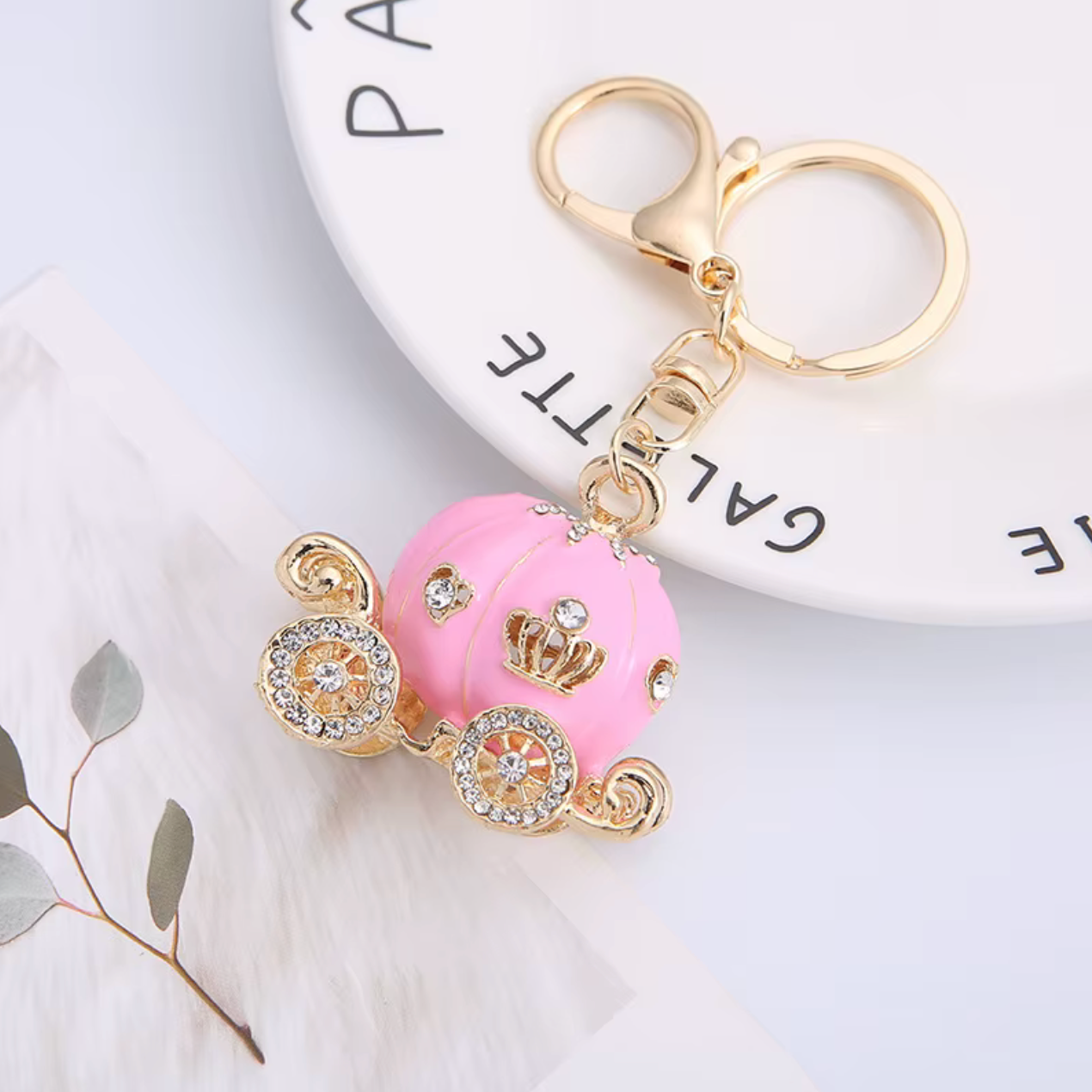 Pink car keychain with gold accents on a white surface