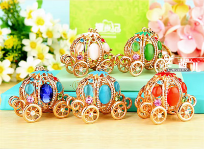 Colorful toy carriages with gemstones on a light surface with flowers in the background