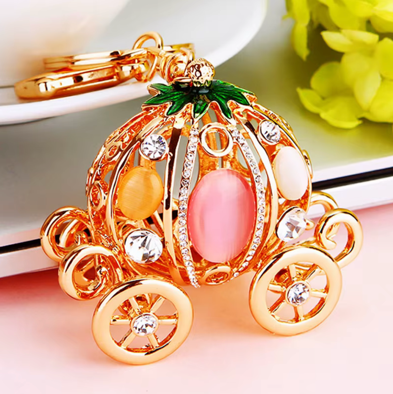 Decorative pumpkin carriage keychain with gold accents on a light background