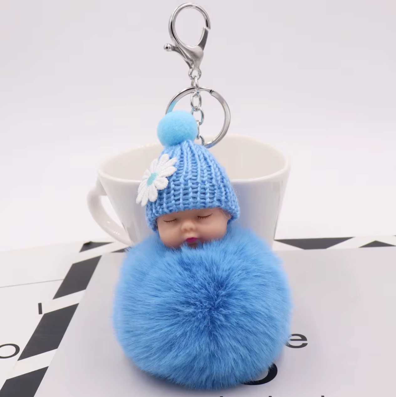 Blue pom-pom keychain with a small figurine on a white background